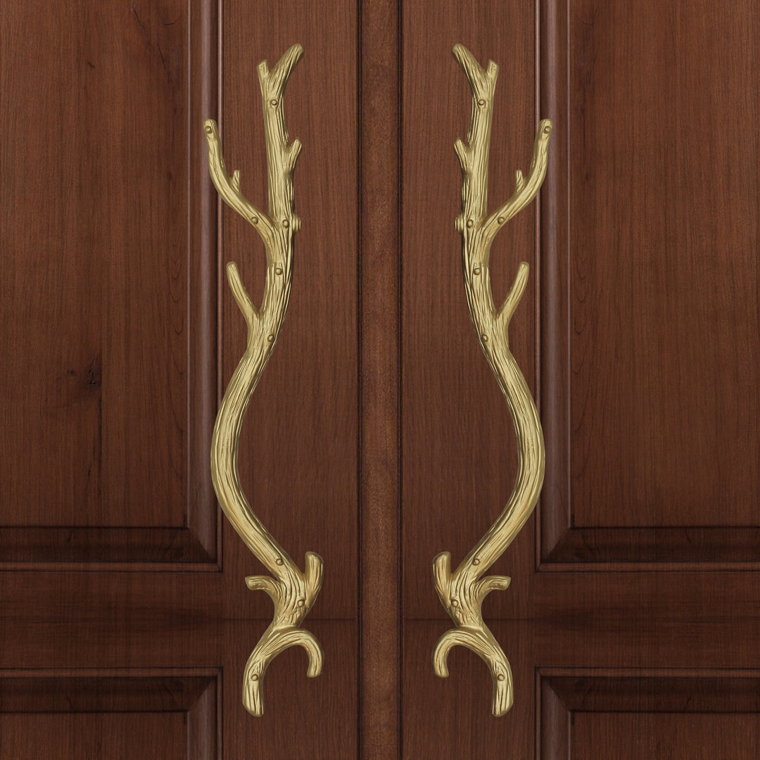 A pair of golden accent pull handles inspired by branches mounted on a closed wooden door