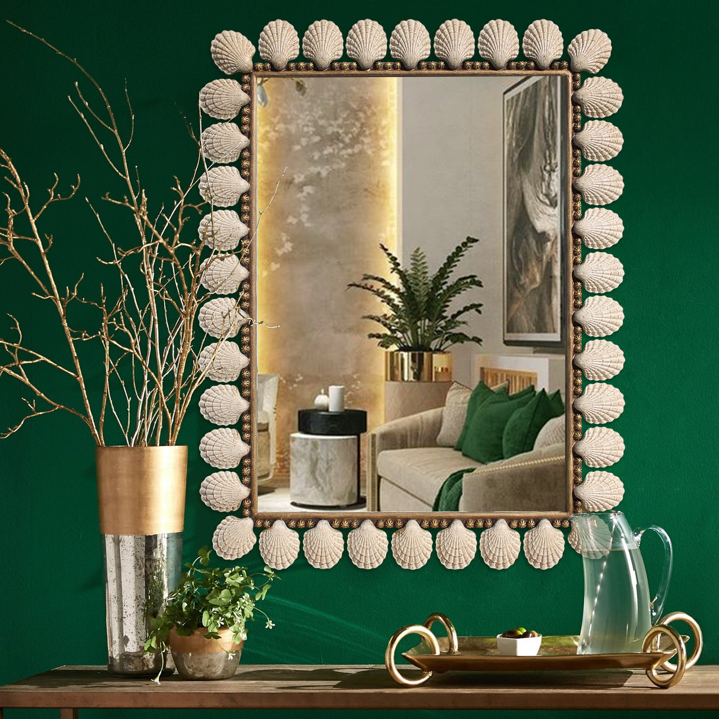 A luxurious rectangular mirror inspired by ocean seashells painted in an antique finish hangs on a green wall