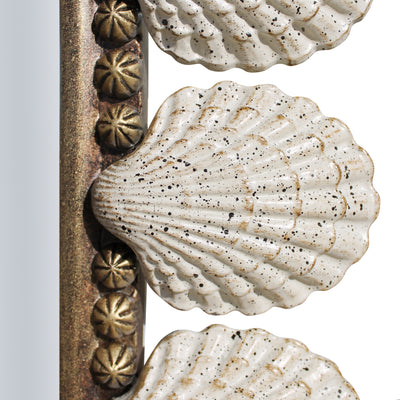Close up of metal seashells painted in a rustic finish on the perimeter of a unique mirror