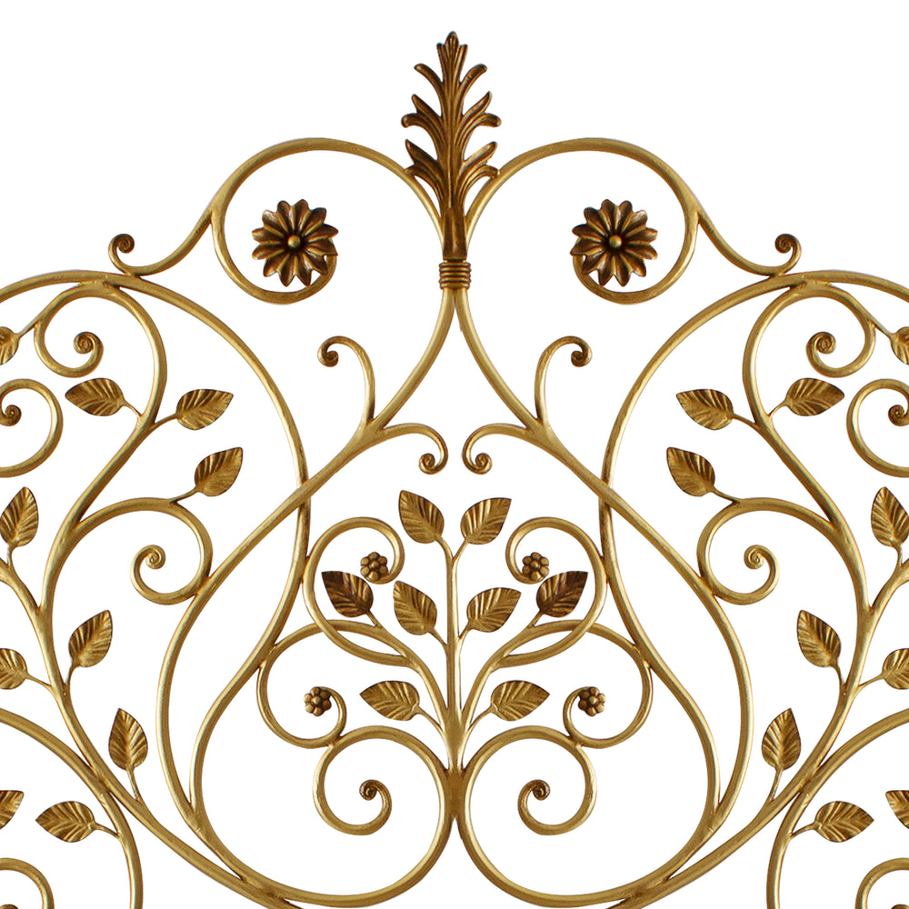 Close up of a wrought iron headboard made up of scrolls, leaves and flowers painted in an antique golden finish