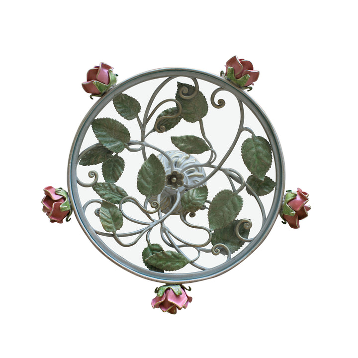 Top view of a round decorative cake plate inspired by leaves and roses; topped with a clear round glass
