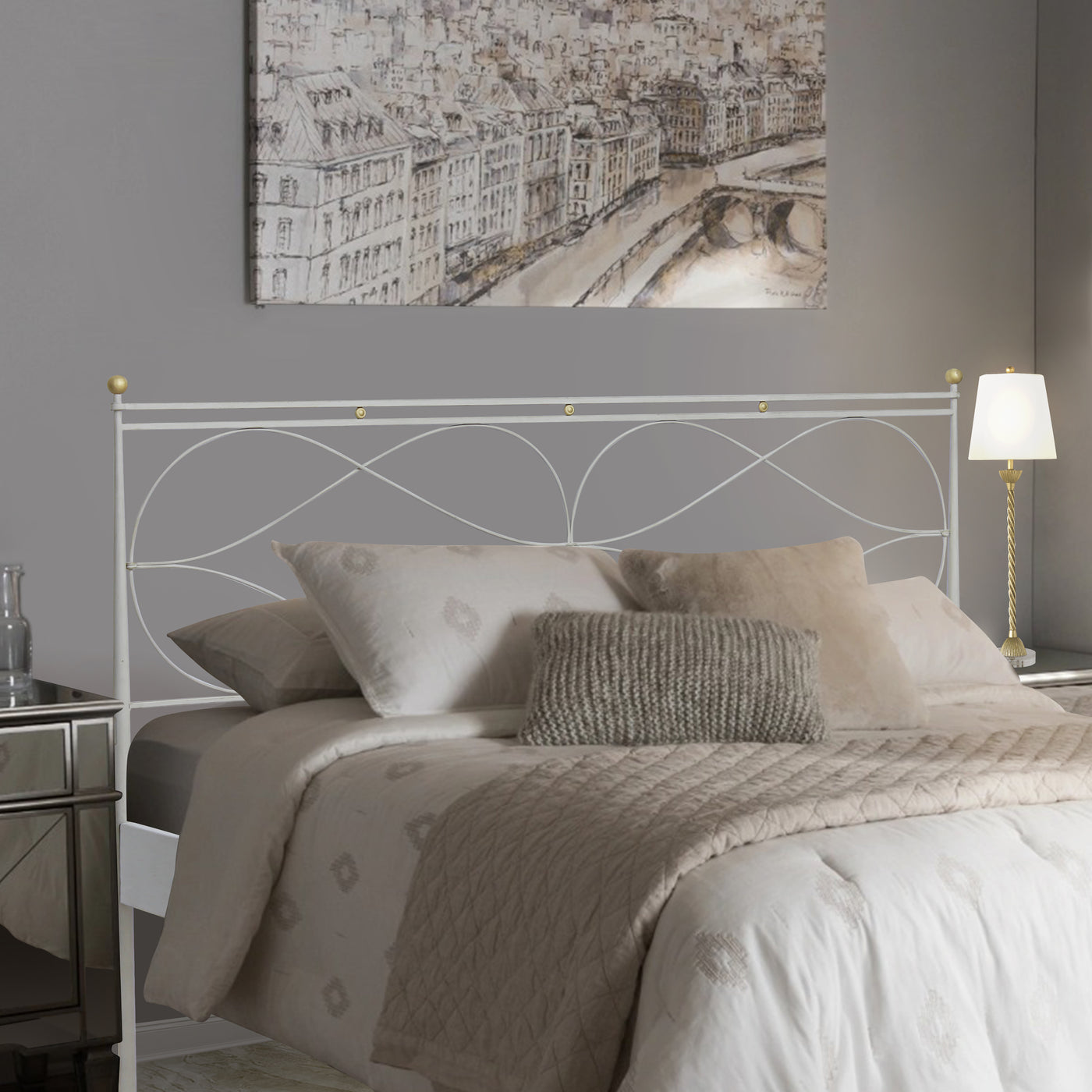 A contemporary wrought iron double bed painted in white and hints of gold, with beige beddings