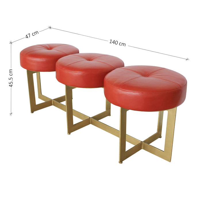 A modern metal golden bench topped with three round cushions upholstered in red leather; with annotated dimensions