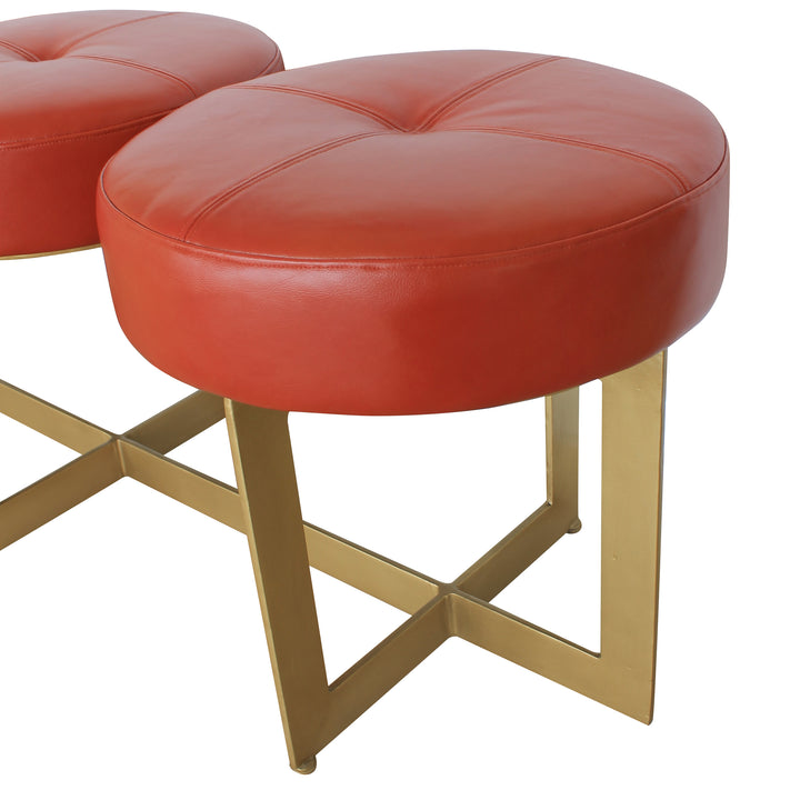 Close up of a unique metal bench with modern styled legs, topped with red leather upholstered cushions