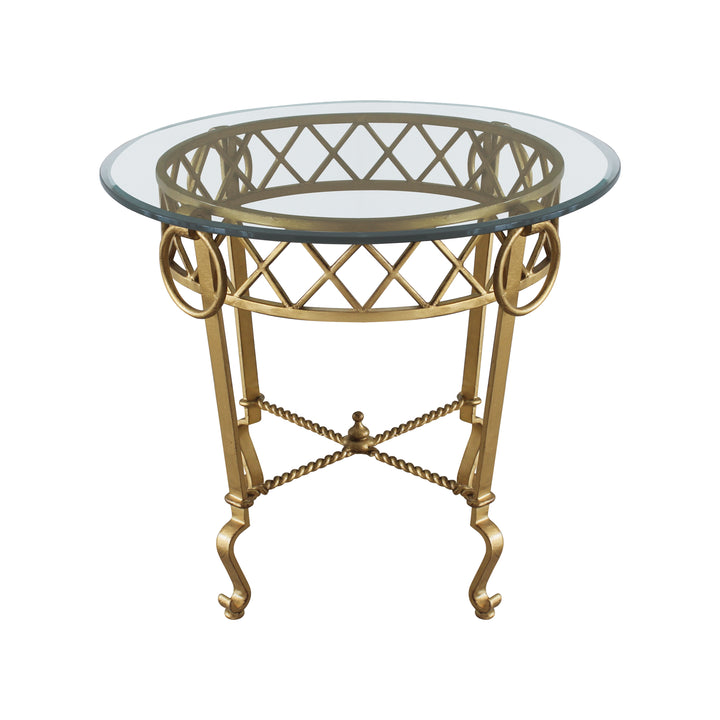 A classical wrought iron table painted in antique gold finish and topped with a clear round glass