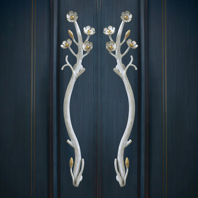 A pair of decorative golden pull handles inspired by nature mounted on a door