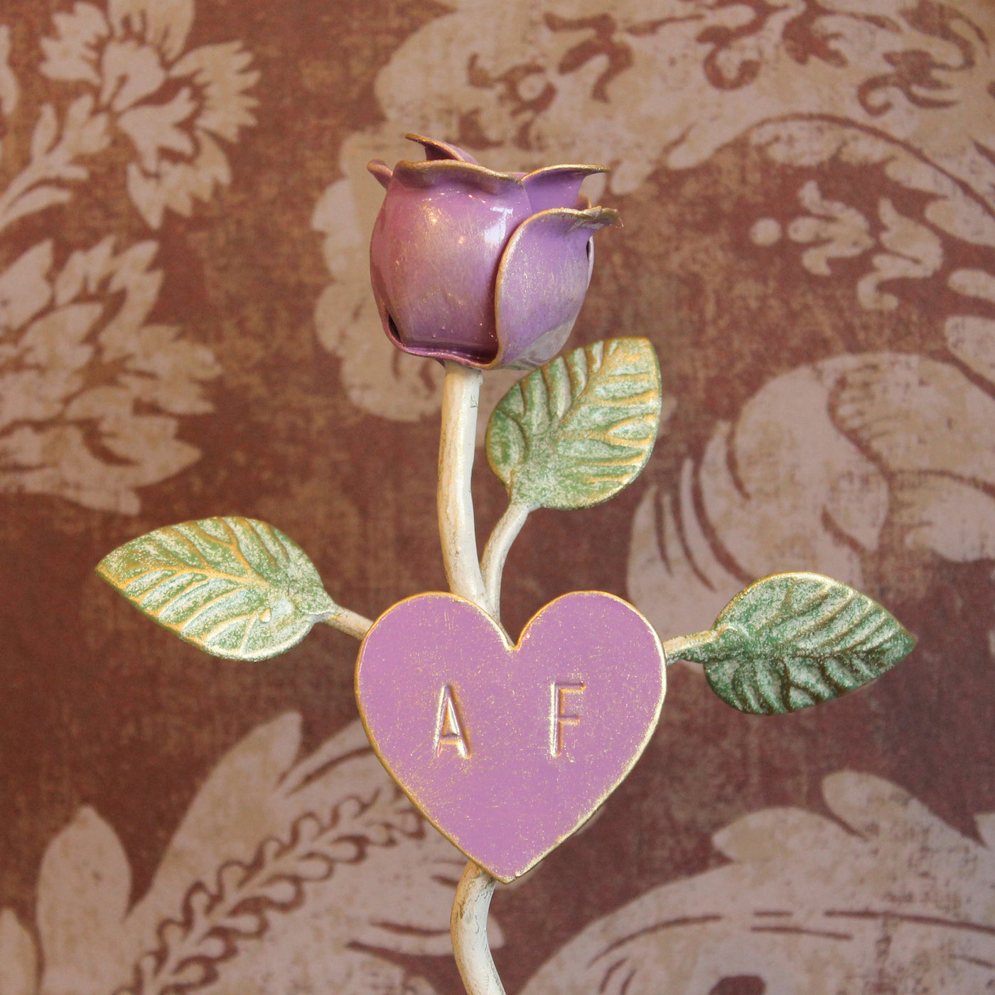 Close up of a decorative wrought iron purple rose stand with engraved initials